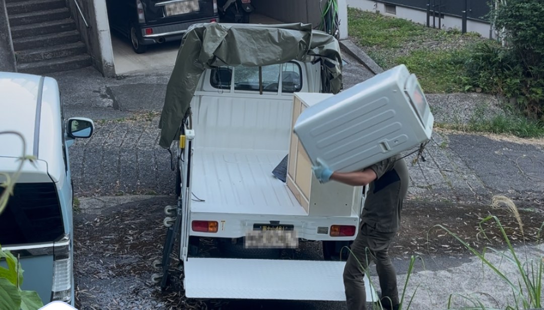 洗濯機を軽トラックへ積み込んでいるところ