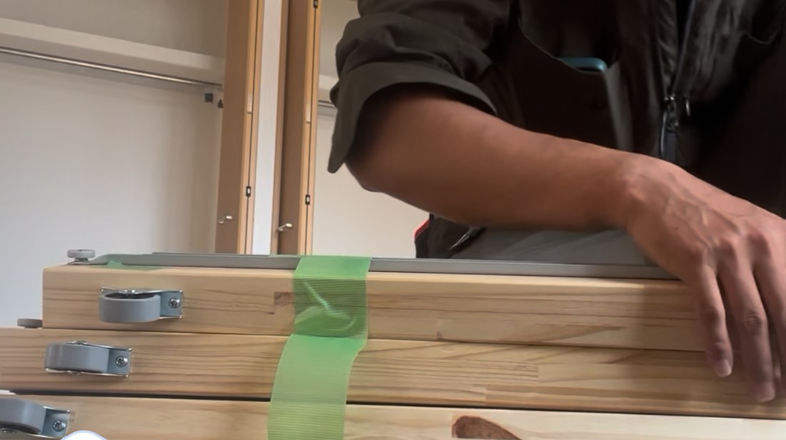 分解した家具の板を、養生テープでまとめているところ