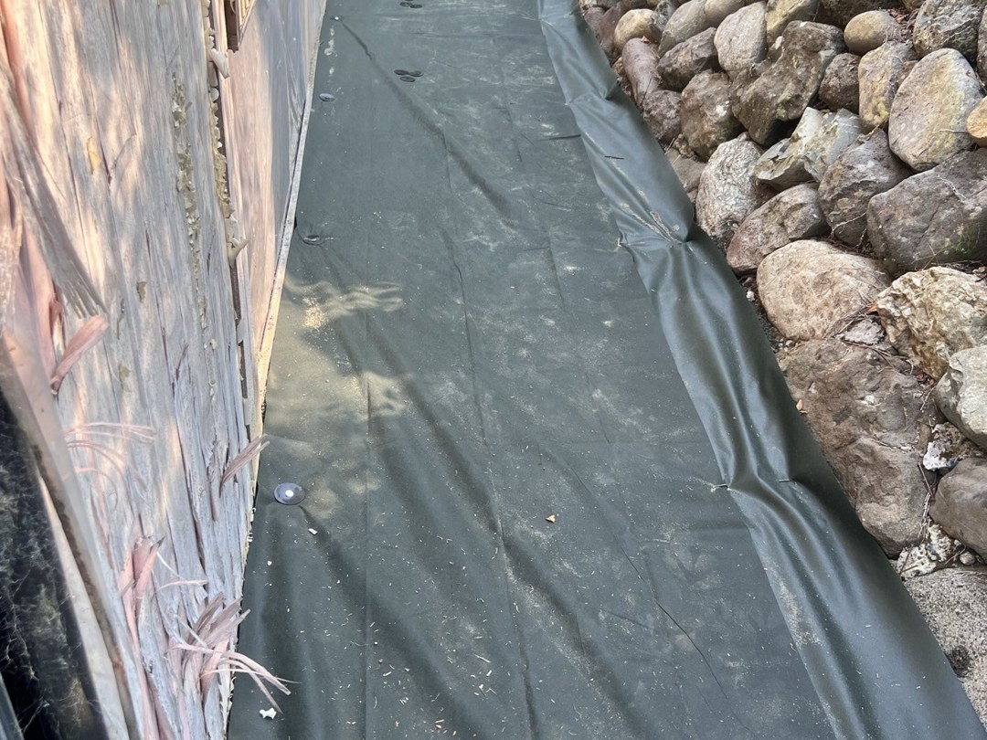 石垣沿いの通路に防草シートを敷き、ピンで留めたところ