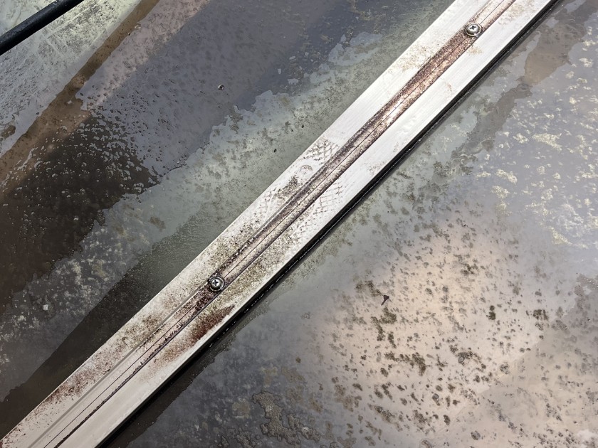 洗浄前のカーポートの屋根。水あかと黒い点々の汚れがこびりついている